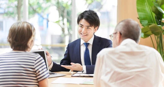 画像:スーツの男性が高齢の夫婦に説明している様子