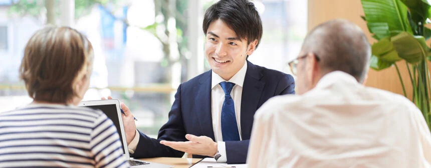 画像:スーツの男性が高齢の夫婦に説明している様子